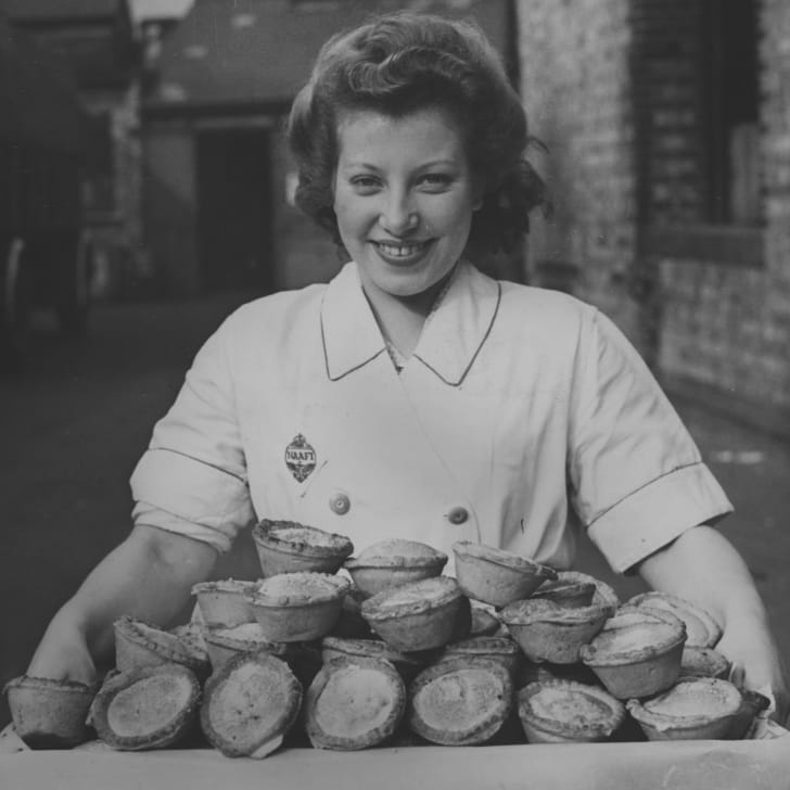 A woman NAAFI worker carrying a tray of apple pies destined for American troops in 1943.